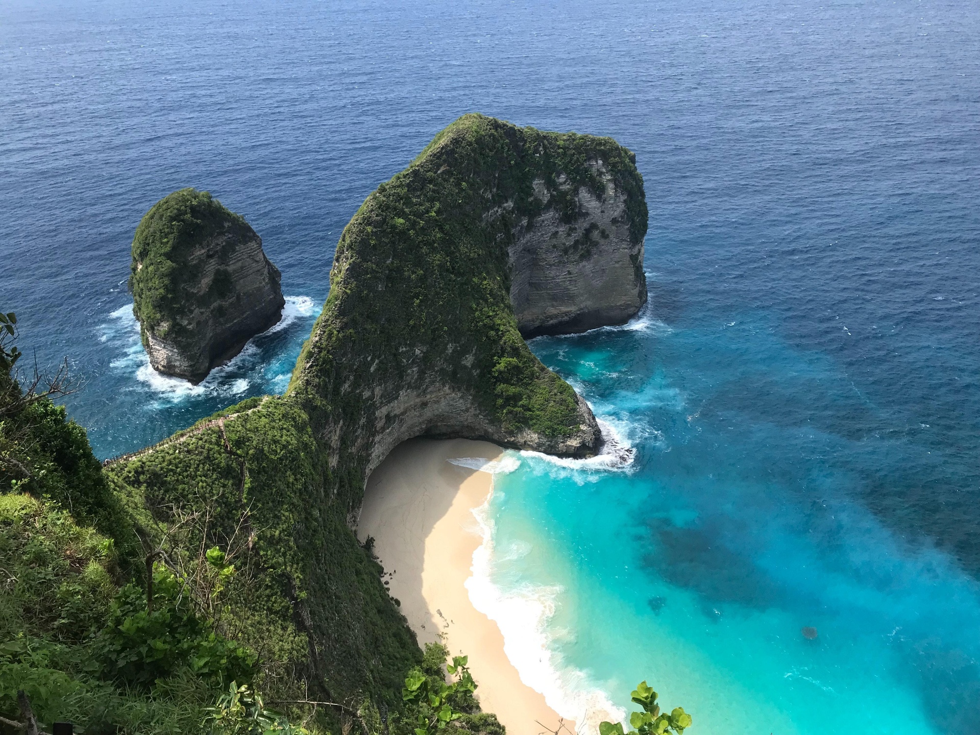 Aerial view of Kelingking Beach on Nusa Penida — turquoise water, white sand cove and dramatic green cliffs